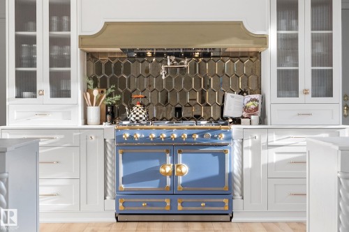 Bar area featuring glass insert cabinets, white cabinetry, backsplash, premium range hood, and gas range - 183 Windermere Drive, Edmonton, AB - 