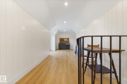 Hallway with light wood finished floors, wood walls, vaulted ceiling, and recessed lighting - 