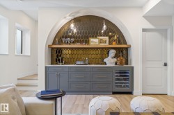 Indoor wet bar with open shelves, gray cabinetry, wine cooler, light wood finished floors, and light stone countertops - 