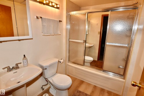 Full bath with wood finished floors and enclosed tub / shower combo - 13910 101A Avenue, Edmonton, AB - Indoor Photo Showing Bathroom