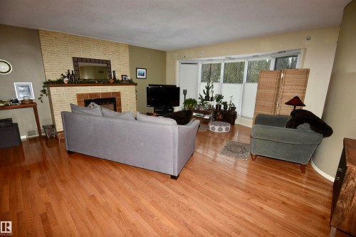 Living room featuring a fireplace, wood finished floors, and a textured ceiling - 13910 101A Avenue, Edmonton, AB - Indoor Photo Showing Living Room With Fireplace