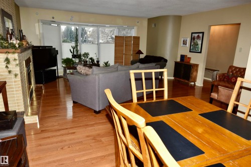 Dining area featuring a brick fireplace and wood finished floors - 13910 101A Avenue, Edmonton, AB - Indoor