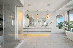 Bathroom with light marble finish flooring, double vanity, a marble finish shower, and a freestanding bath - 