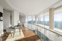 Corridor with recessed lighting, a skyline view, wood finished floors, expansive windows, and a tray ceiling - 