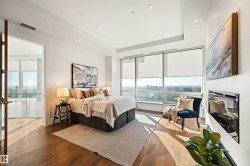 Bedroom with wood finished floors, a raised ceiling, recessed lighting, a glass covered fireplace, and a city view - 