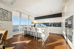 Kitchen with modern cabinets, a kitchen bar, an island with sink, dark wood finished floors, and white cabinetry - 