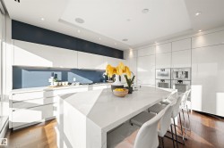 Kitchen with modern cabinets, white cabinetry, light stone counters, and recessed lighting - 