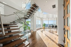 Stairs with healthy amount of natural light, a high ceiling, hardwood / wood-style flooring, and recessed lighting - 