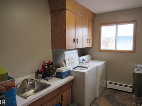 Washroom featuring baseboard heating, independent washer and dryer, and cabinet space - 5016 51 Street, Barrhead, AB - Indoor Photo Showing Laundry Room