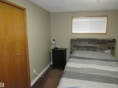 Carpeted bedroom with a textured ceiling and a closet - 5016 51 Street, Barrhead, AB - Indoor Photo Showing Bedroom