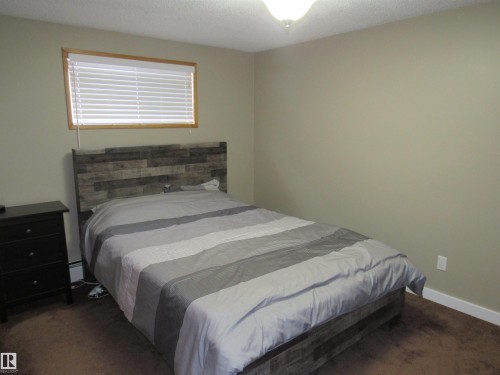 Bedroom featuring dark colored carpet, a textured ceiling, and a baseboard radiator - 5016 51 Street, Barrhead, AB - Indoor Photo Showing Bedroom