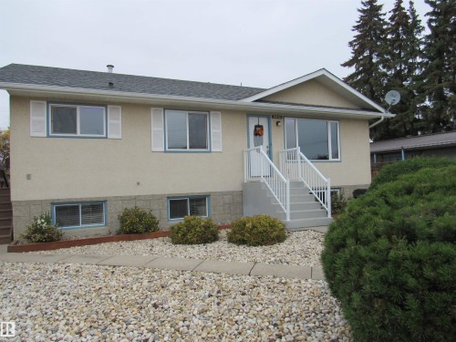 View of front facade with stucco siding and a shingled roof - 5016 51 Street, Barrhead, AB - Outdoor With Facade