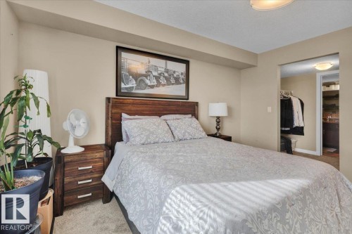 Bedroom with light carpet, a spacious closet, and a textured ceiling - 305 5029 Edgemont Boulevard, Edmonton, AB - Indoor Photo Showing Bedroom