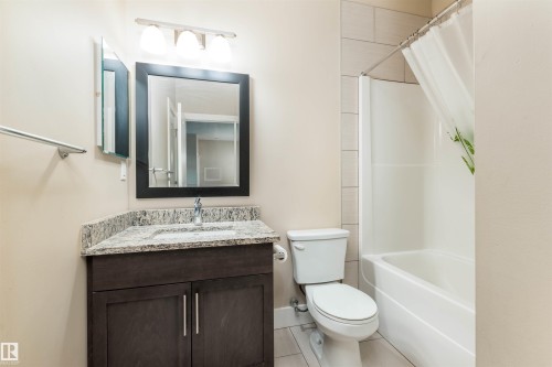 Full bath featuring vanity, shower / bath combo with shower curtain, and light tile patterned floors - 140 6079 Maynard Way, Edmonton, AB - Indoor Photo Showing Bathroom
