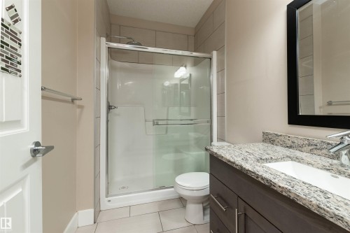 Full bath featuring vanity, a shower stall, and light tile patterned floors - 140 6079 Maynard Way, Edmonton, AB - Indoor Photo Showing Bathroom
