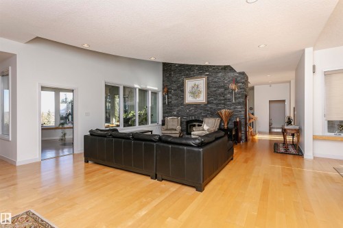 Living area featuring a textured ceiling, a stone fireplace, light wood finished floors, and recessed lighting - 19103 Ellerslie Road Sw, Edmonton, AB - Indoor Photo Showing Living Room With Fireplace