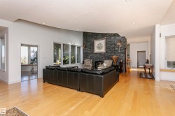 Living area featuring a textured ceiling, a stone fireplace, light wood finished floors, and recessed lighting - 