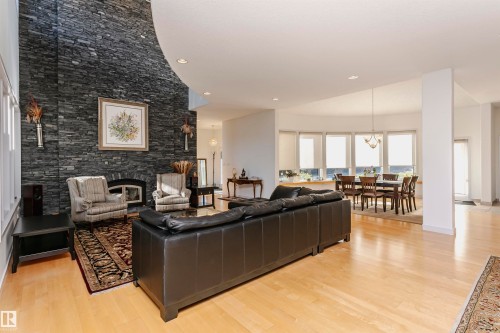 Living area with a stone fireplace, light wood finished floors, recessed lighting, a chandelier, and a towering ceiling - 19103 Ellerslie Road Sw, Edmonton, AB - Indoor Photo Showing Living Room With Fireplace