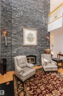 Living area with a glass covered fireplace, light wood-type flooring, and a towering ceiling - 