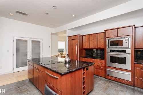 Kitchen featuring dark stone counters, a center island, appliances with stainless steel finishes, a warming drawer, and recessed lighting - 19103 Ellerslie Road Sw, Edmonton, AB - Indoor Photo Showing Kitchen