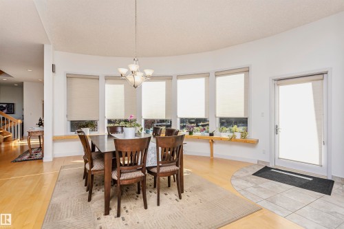 Dining area featuring stairs, light wood finished floors, and a chandelier - 19103 Ellerslie Road Sw, Edmonton, AB - Indoor Photo Showing Dining Room