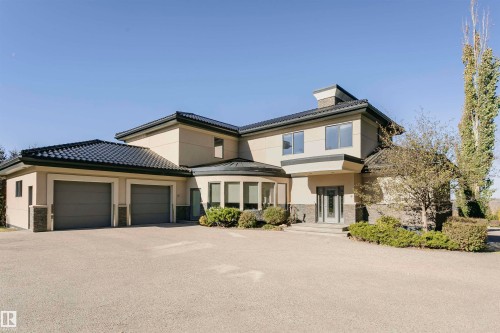 View of front of house featuring stucco siding, a garage, stone siding, and driveway - 19103 Ellerslie Road Sw, Edmonton, AB - Outdoor