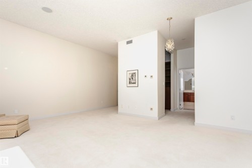 Unfurnished room with a chandelier, light carpet, and a textured ceiling - 19103 Ellerslie Road Sw, Edmonton, AB - Indoor Photo Showing Other Room