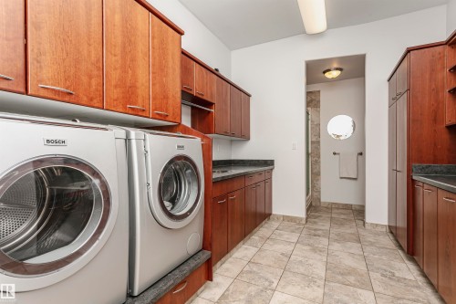Laundry room with cabinet space, washing machine and clothes dryer, and light tile patterned floors - 19103 Ellerslie Road Sw, Edmonton, AB - Indoor Photo Showing Laundry Room