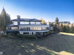 Back of house featuring a chimney, a balcony, a yard, and stucco siding - 