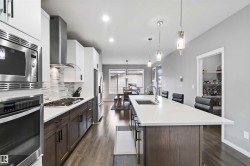 Kitchen featuring dark brown cabinets, stainless steel appliances, a large island, a kitchen bar, and recessed lighting - 