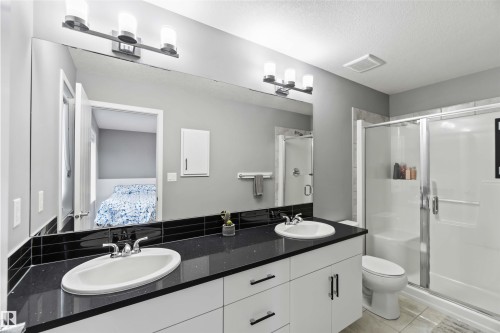Full bathroom featuring double vanity, light tile patterned flooring, a stall shower, ensuite bath, and a textured ceiling - 17816 59 Street, Edmonton, AB - Indoor Photo Showing Bathroom