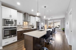 Kitchen with tasteful backsplash, a breakfast bar, appliances with stainless steel finishes, white cabinets, and dark brown cabinets - 