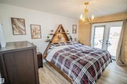 Bedroom featuring light wood-style floors, access to outside, wood walls, french doors, and a chandelier - 
