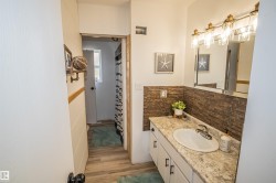 Full bath with vanity, a shower with curtain, light wood-style floors, and tile walls - 