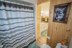 Bathroom featuring a shower with shower curtain, vanity, light wood-style floors, and wooden walls - 
