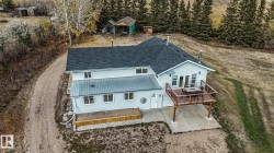 View of front of property with a wooden deck, a metal roof, french doors, and a patio - 
