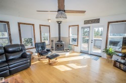 Living room with a wood stove, light wood-type flooring, and a ceiling fan - 