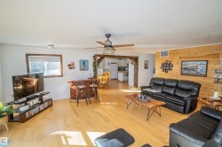 Living area with wooden walls, light wood-type flooring, and ceiling fan - 