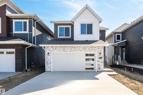 View of front of home with board and batten siding, concrete driveway, roof with shingles, and a garage - 3331 Chickadee Drive, Edmonton, AB - Outdoor With Facade