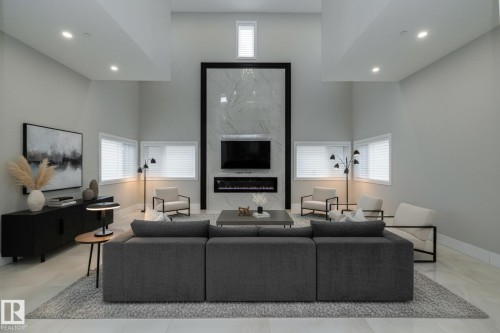 Spacious living area featuring high ceilings, recessed lighting, and a modern fireplace with a marble-effect surround - 14 3466 Keswick Boulevard, Edmonton, AB - Indoor With Fireplace