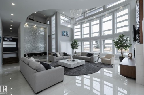 The spacious living area features high ceilings, expansive windows providing abundant natural light, and polished floors - 14 3466 Keswick Boulevard, Edmonton, AB - Indoor