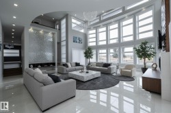 The spacious living area features high ceilings, expansive windows providing abundant natural light, and polished floors - 