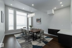 This dining area features rich hardwood flooring, a contemporary light fixture, and a large window arrangement that provides ample natural light - 