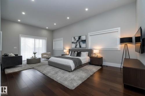 This expansive room features dark hardwood flooring, recessed lighting, and large windows with blinds - 14 3466 Keswick Boulevard, Edmonton, AB - Indoor Photo Showing Bedroom