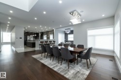 Spacious open-concept living area featuring dark hardwood floors, recessed lighting, and large windows providing natural light - 
