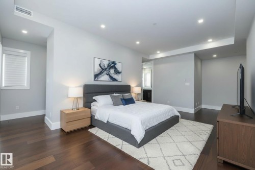 This property features dark hardwood flooring, recessed lighting, and a window with white blinds - 14 3466 Keswick Boulevard, Edmonton, AB - Indoor Photo Showing Bedroom