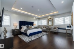This bedroom features dark hardwood floors, white walls, and a tray ceiling with recessed lighting - 