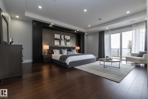 This room features dark hardwood flooring, recessed lighting, and a large glass door leading to an outdoor space - 14 3466 Keswick Boulevard, Edmonton, AB - Indoor Photo Showing Bedroom