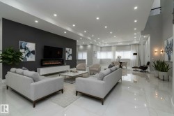 This expansive living area features bright recessed lighting, a dark accent wall with an integrated fireplace, and sleek polished tile flooring - 