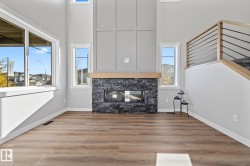 Unfurnished living room featuring a fireplace, a towering ceiling, and wood finished floors - 